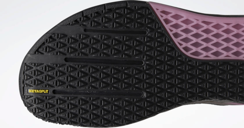 Outsole closeup of the Reebok Nano 9 Men's CrossFit Training Shoe in BLACK / COLD GREY 7 / POSH PINK.  You can see that the sole is flat with minimal tread - and that means maximum contact area with the floor.  These are definitely indoor gym shoes - rather than trail runners - but that's OK because most of CrossFit takes place in the box.