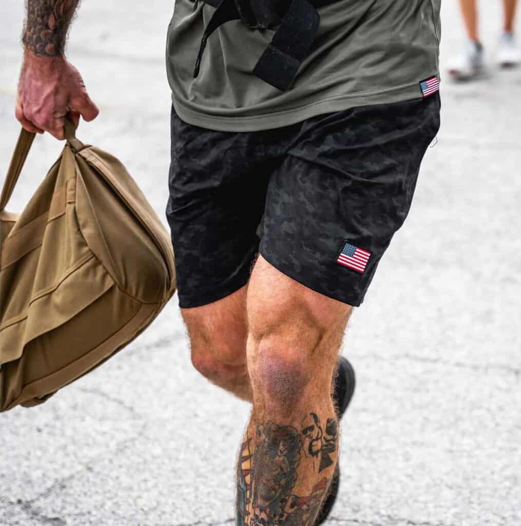 GORUCK Men’s American Training Shorts dark camo walking with a ruckbag