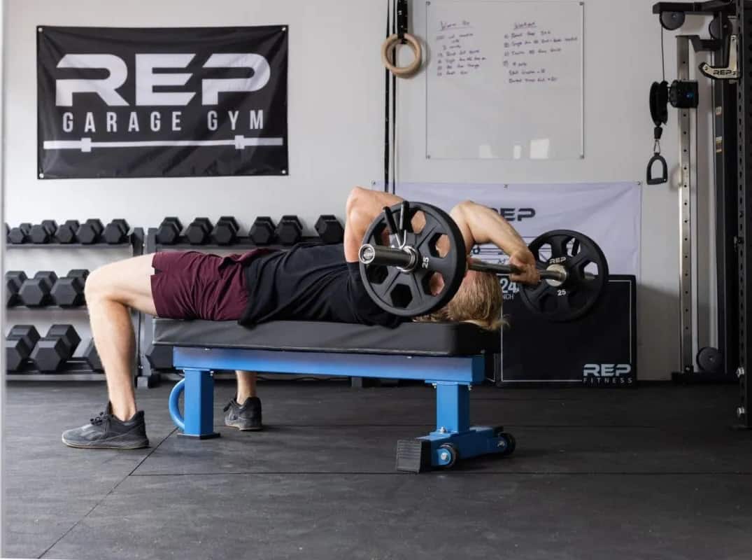 Rep Fitness FB-5000 Comp Flat Bench with a barbell
